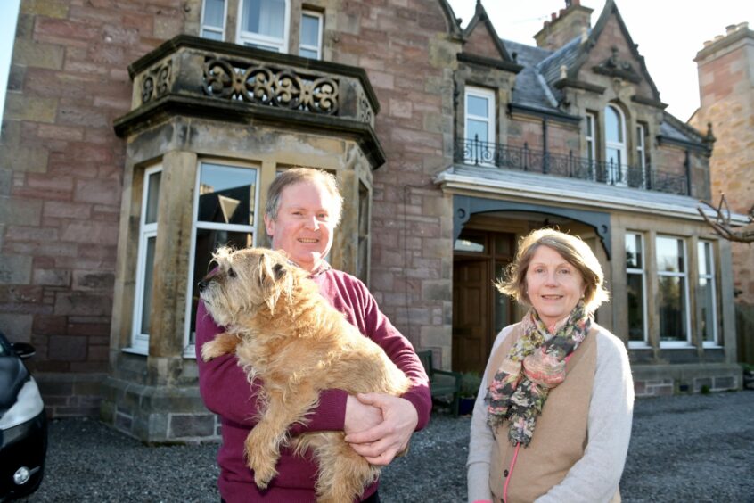 Photo of the house owners and their dog in front of the building's façade