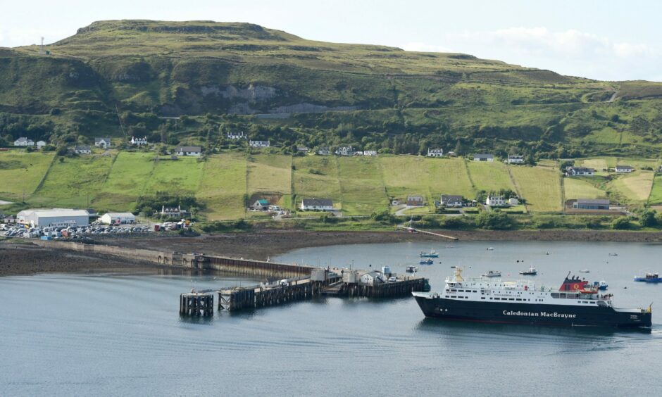 Uig Harbour in the north of Skye. The picture shows a ferry pulling into the pier. Houses can be seen along the waterfront. 