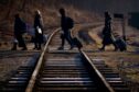 A family from Ukraine walk over a railway line with their luggage after crossing a border point into Poland at Kroscienko, in the south east of the country. Victoria Jones/PA Wire