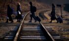 A family from Ukraine walk over a railway line with their luggage after crossing a border point into Poland at Kroscienko, in the south east of the country. Victoria Jones/PA Wire