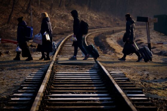 A family from Ukraine walk over a railway line with their luggage after crossing a border point into Poland at Kroscienko, in the south east of the country. Victoria Jones/PA Wire