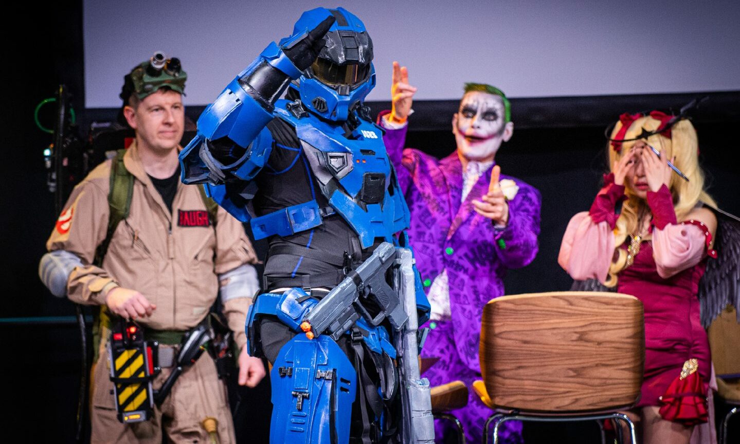 Cosplayers on stage, a Ghostbuster, Halo character, the Joker and an anime character.