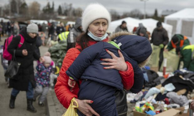 A woman carries her child as she arrives at the Medyka border crossing after fleeing from the Ukraine, in Poland.  Picture by AP Photo/Visar Kryeziu