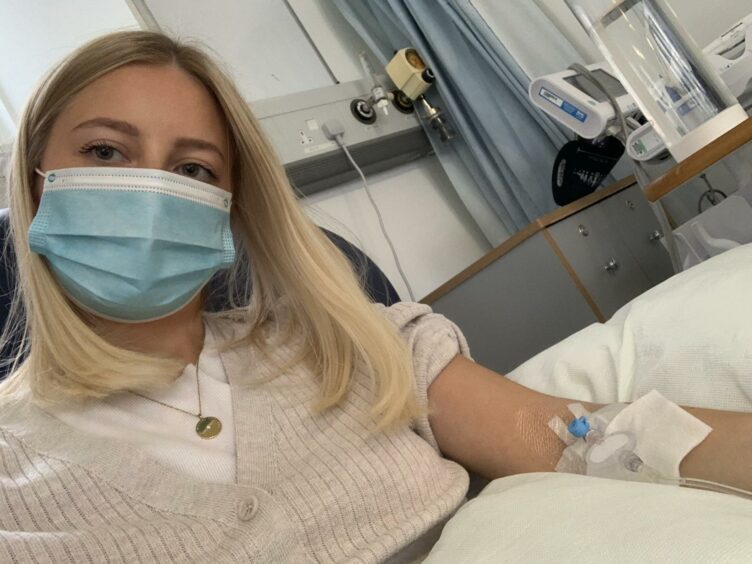 Olivia Bonner lying in a hospital bed with mask on getting her Infliximab infusion which can be seen on her arm