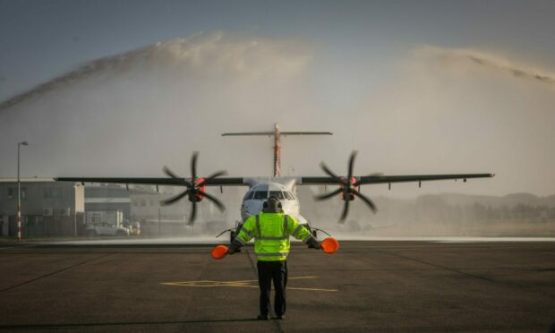 Loganair aircraft being guided to the stand by a batman.