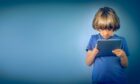 Child on blue background holding a blue iPad