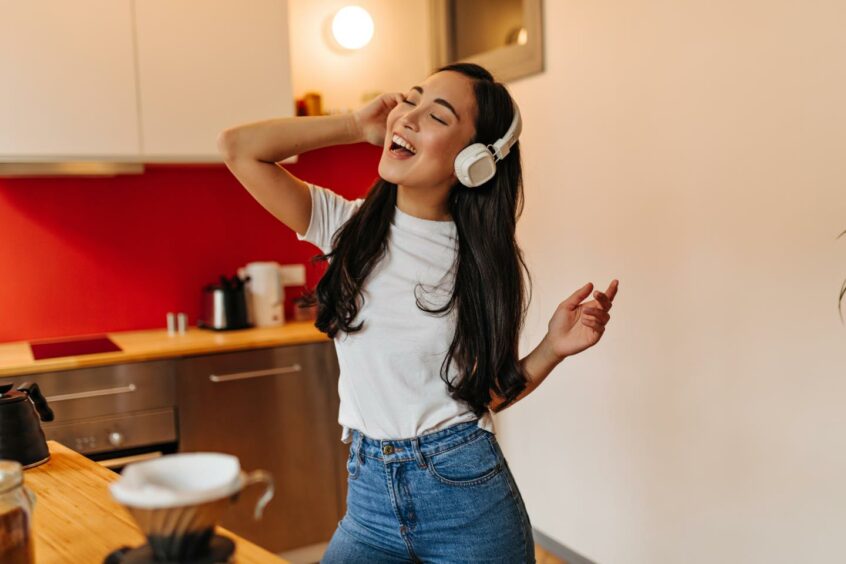 Woman with headphones dancing in her kitchen