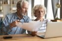 Elderly couple organising paperwork for how to avoid paying care home fees