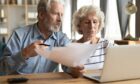 Elderly couple organising paperwork for how to avoid paying care home fees