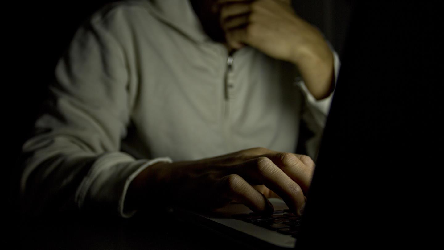 Anonymous male on a laptop at night. 