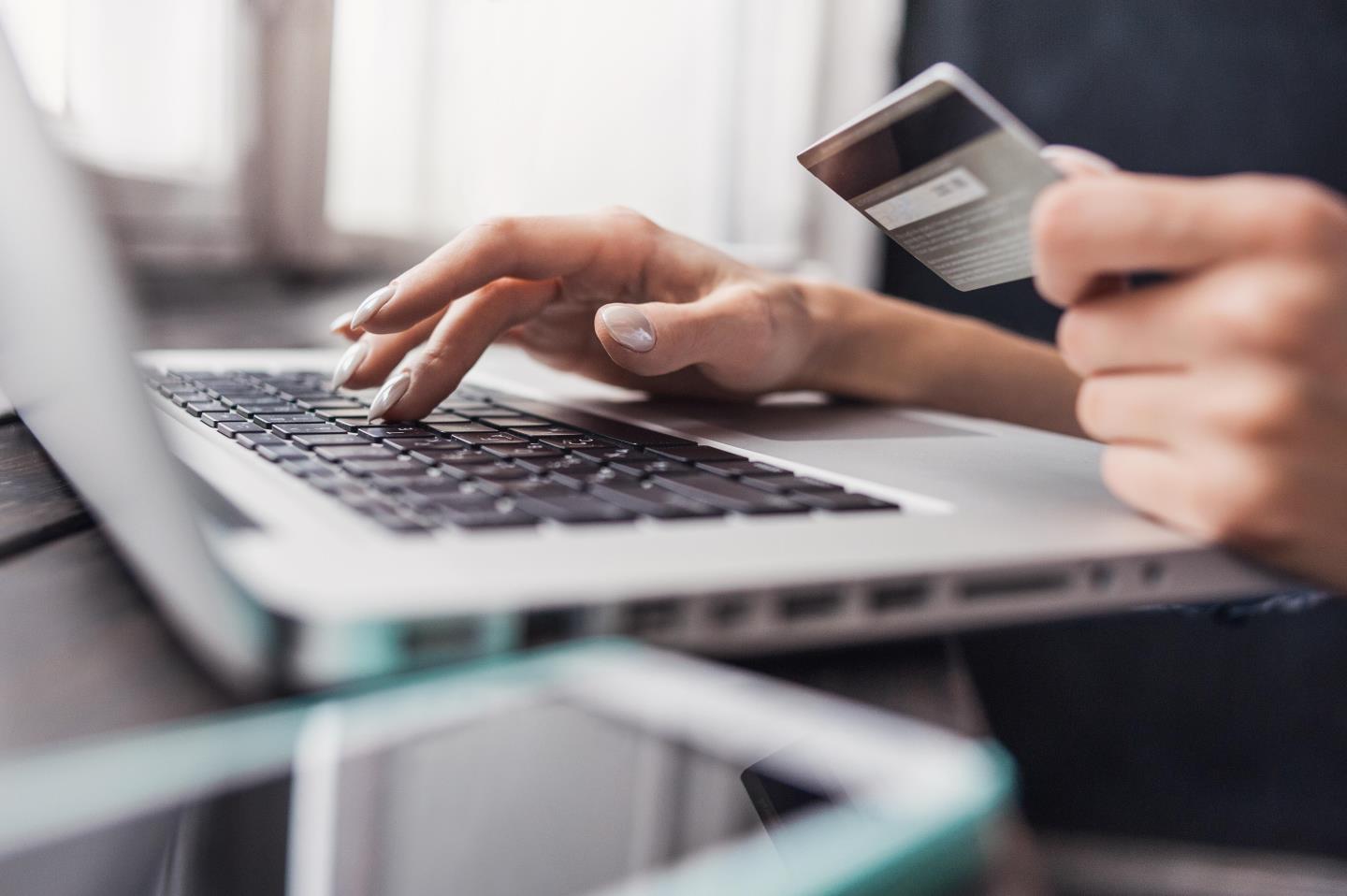 Close up of Hand holding credit card and using laptop. 