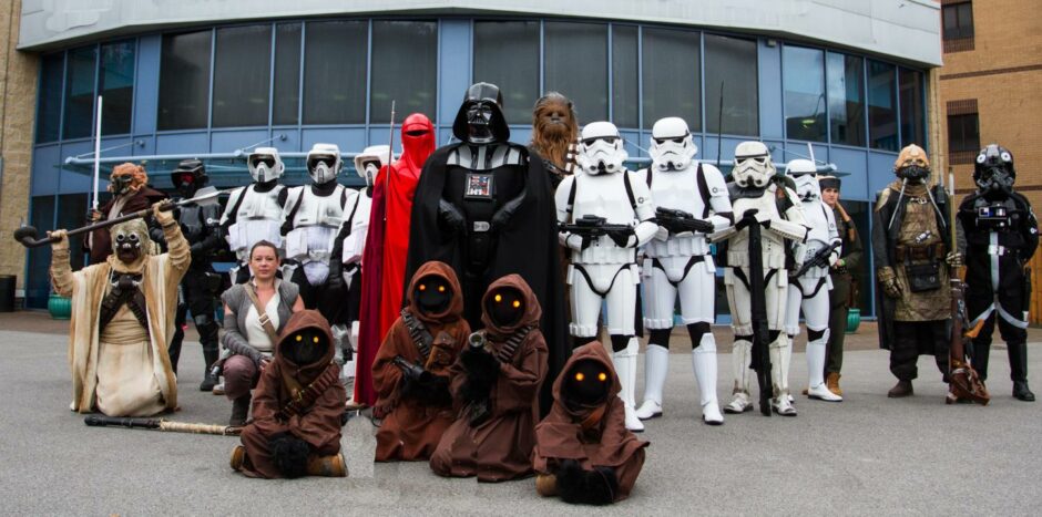 A group of Star Wars fans cosplaying at Comic Con as characters like Darth Vader, Chewbacca and Stormtroopers.