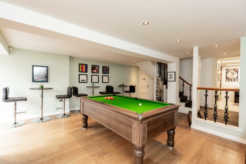 The basement has modern décor, wooden flooring and a pool table.