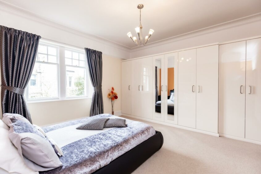 A spacious double bedroom with double windows, light carpet floors and in-build wardrobe.