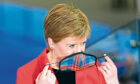 Nicola Sturgeon puts on her face mask.  Picture by Stuart Wallace/Shutterstock