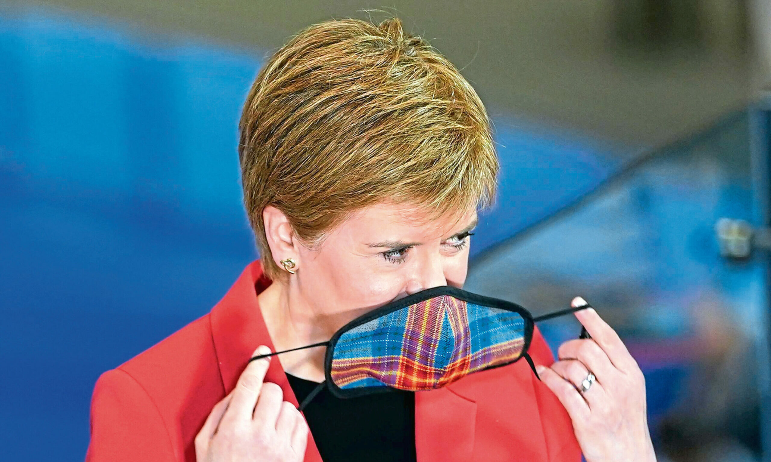Nicola Sturgeon puts on her face mask.  Picture by Stuart Wallace/Shutterstock