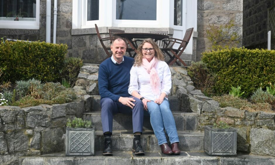 Rod and Mary Agnew sitting on stone steps in the garden of their property.