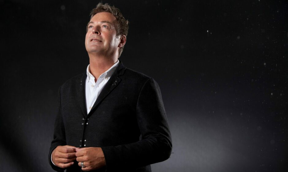 Julian Clary on a black backdrop, looking upward