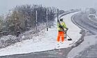 Worker cutting grass in snow at side of A9.