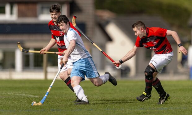 Skye's Jordan Murchison gets away from Lachlan Smith and Ali Mackintosh (both Glenurquhart). Image: Neil Paterson.