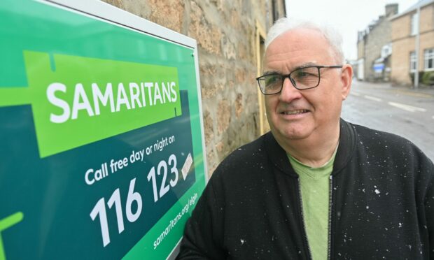 John Knight standing next to Samaritans sign