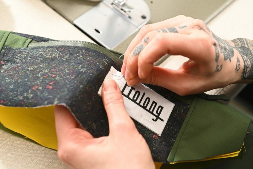 Lucia stitching a "Prolong" tag to one of her products.