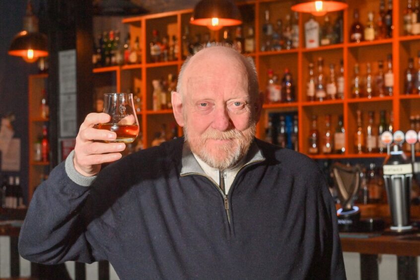 Jim Sandison holding up a glass of whisky.