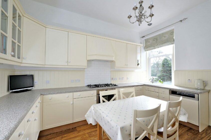 The dining area with a table for four in front of the stove and cream-colour cabinets.