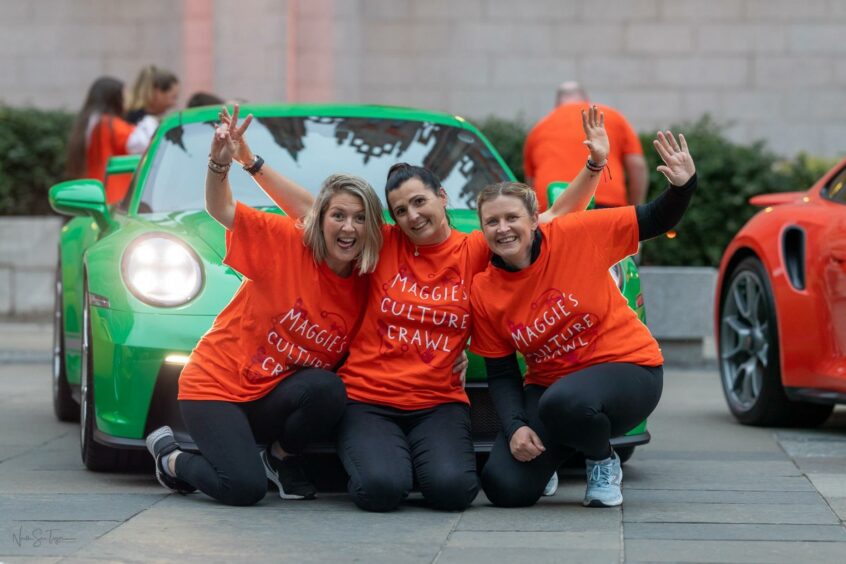 Culture Crawl Walkers posing in front of a car wearing 'Maggie's Culture Crawl' shirts