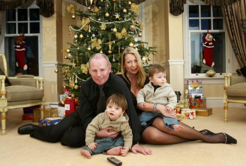 Stewart Milne and his wife Joanne with their two children in front of a Christmas tree.