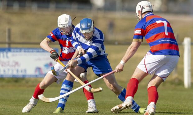Newtonmore's Conor Jones (centre) up against Ruaridh Anderson (left) and Roddy Young (both Kingussie).  Image: Neil Paterson.