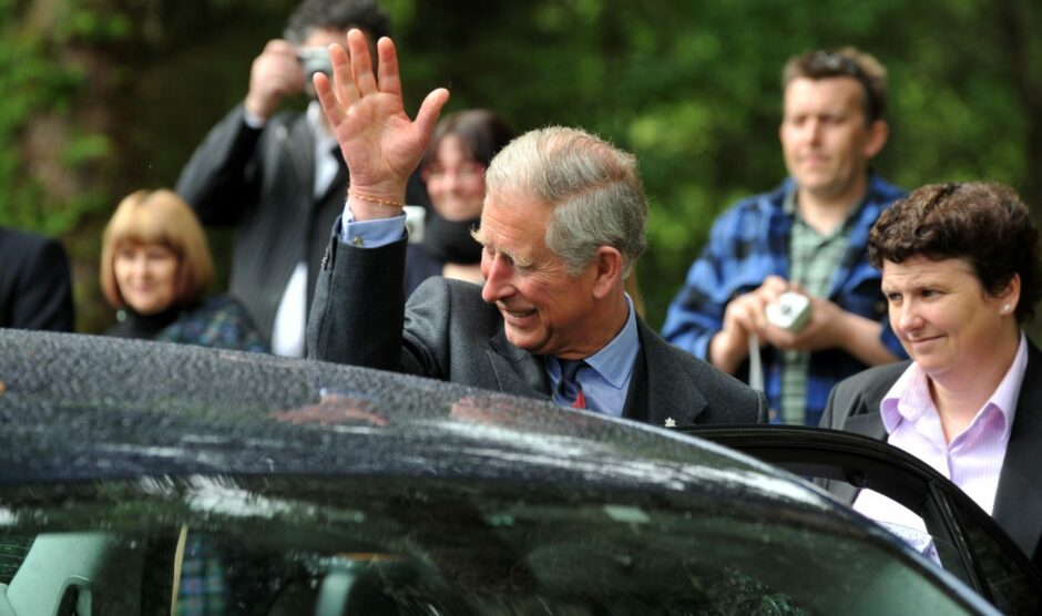 Prince Charles waving outside a car.