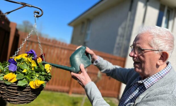 Resident of Jesmond Care Home watering flowers in the sunshine.