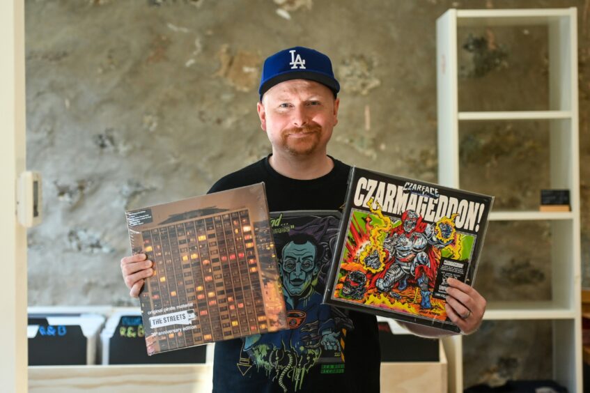 Nick Duthie holding two records at Aberdeen cafe Red Robin Records