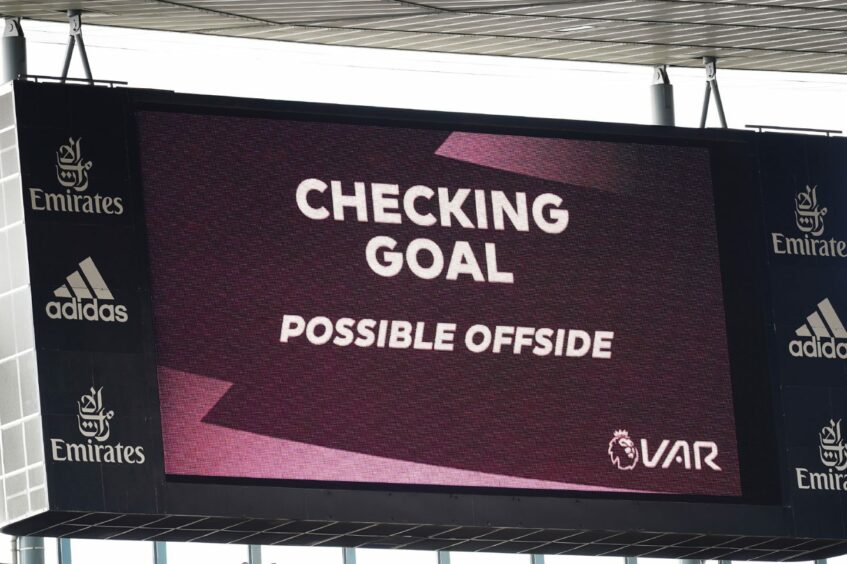 Stadium screen showing text "Checking goal. Possible offside".