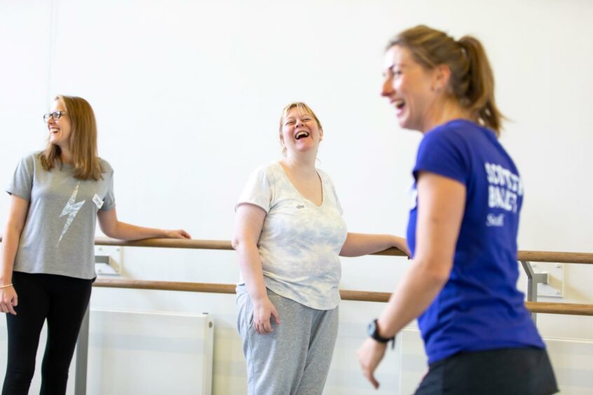 Three women laughing as they do ballet