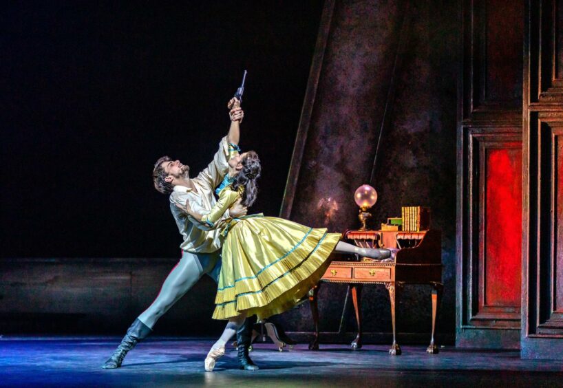 The dancers reaching for the gun prop which is aimed at the ceiling