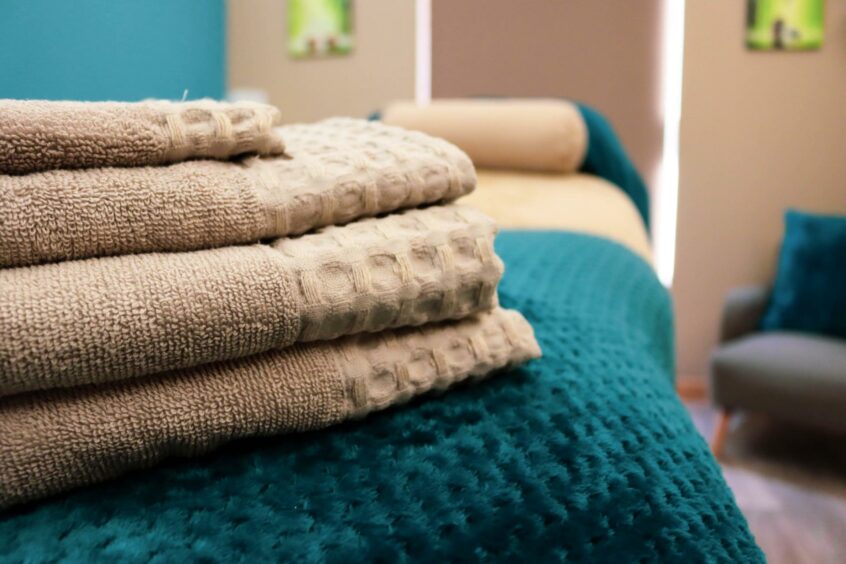 Picture shows: Neatly folded towels on a massage bed.