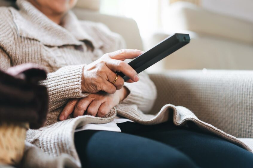 Elderly woman holding tv remote