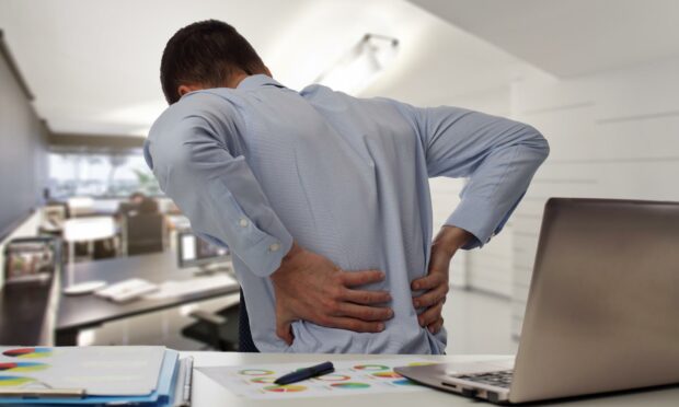Man in a white shirt with back pain in an office