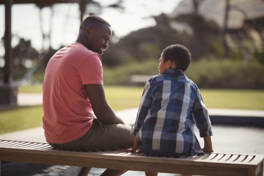 A father and son discuss how to deal with bullies at school on a walk outside