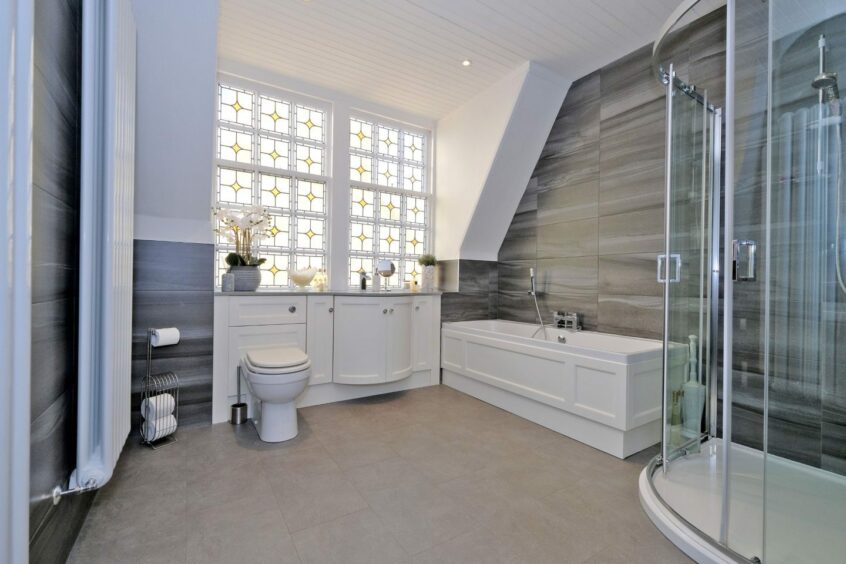 Contemporary bathroom with stained glass windows, bath tub and standing shower.