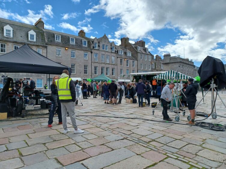 Castlegate during Granite Harbour filming, with cast, crew and extras spread out for a protest scene.