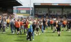 Dundee United fans run on the pitch during a cinch Premiership match between Ross County and Dundee United at The Global Energy Stadium.