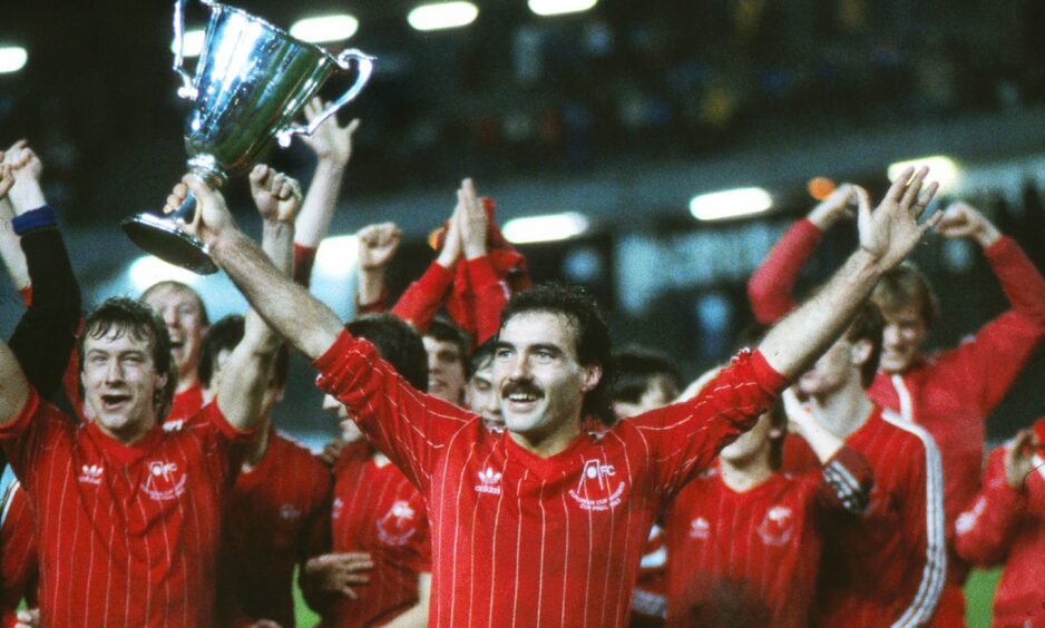 Aberdeen legend Willie Miller lifts a trophy.