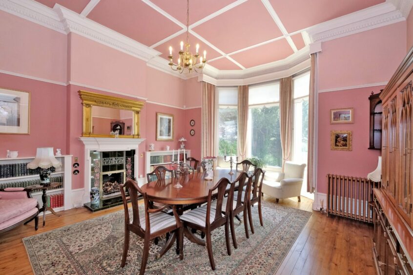 The livingroom with ornate cornices, pink walls and wooden details. 