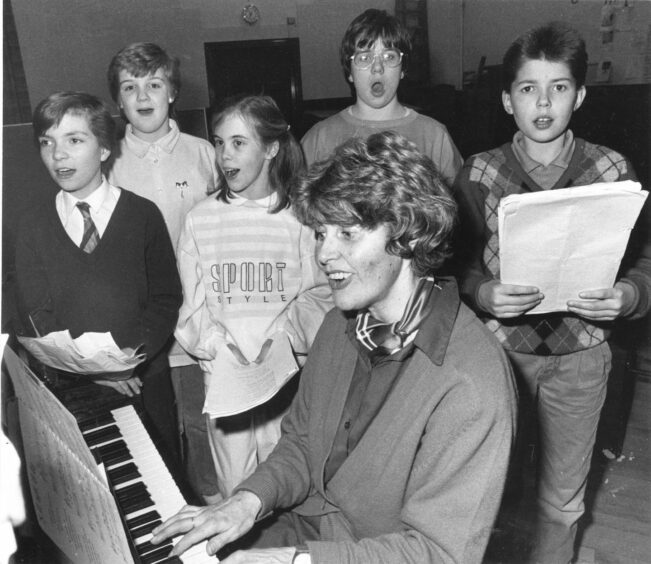 Holburn West Church children sing along as the assistant choir leader plays the piano.
