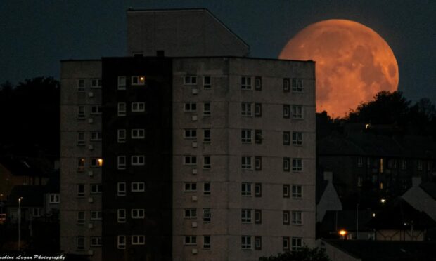Blood moon behind city buildings.