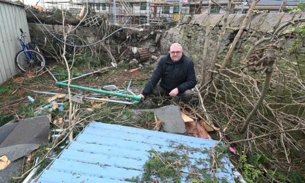 Gordon Ledingham among broken chunks of metal, plastic and stone left strewn across his garden after Storm Arwen