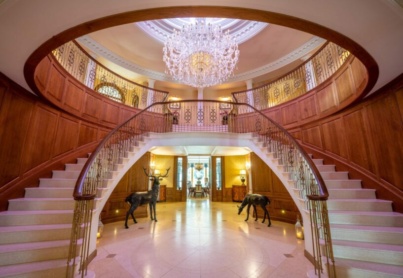 Dalhebity House's horseshoe staircase also features a large chandelier, and wooden panelling. 
